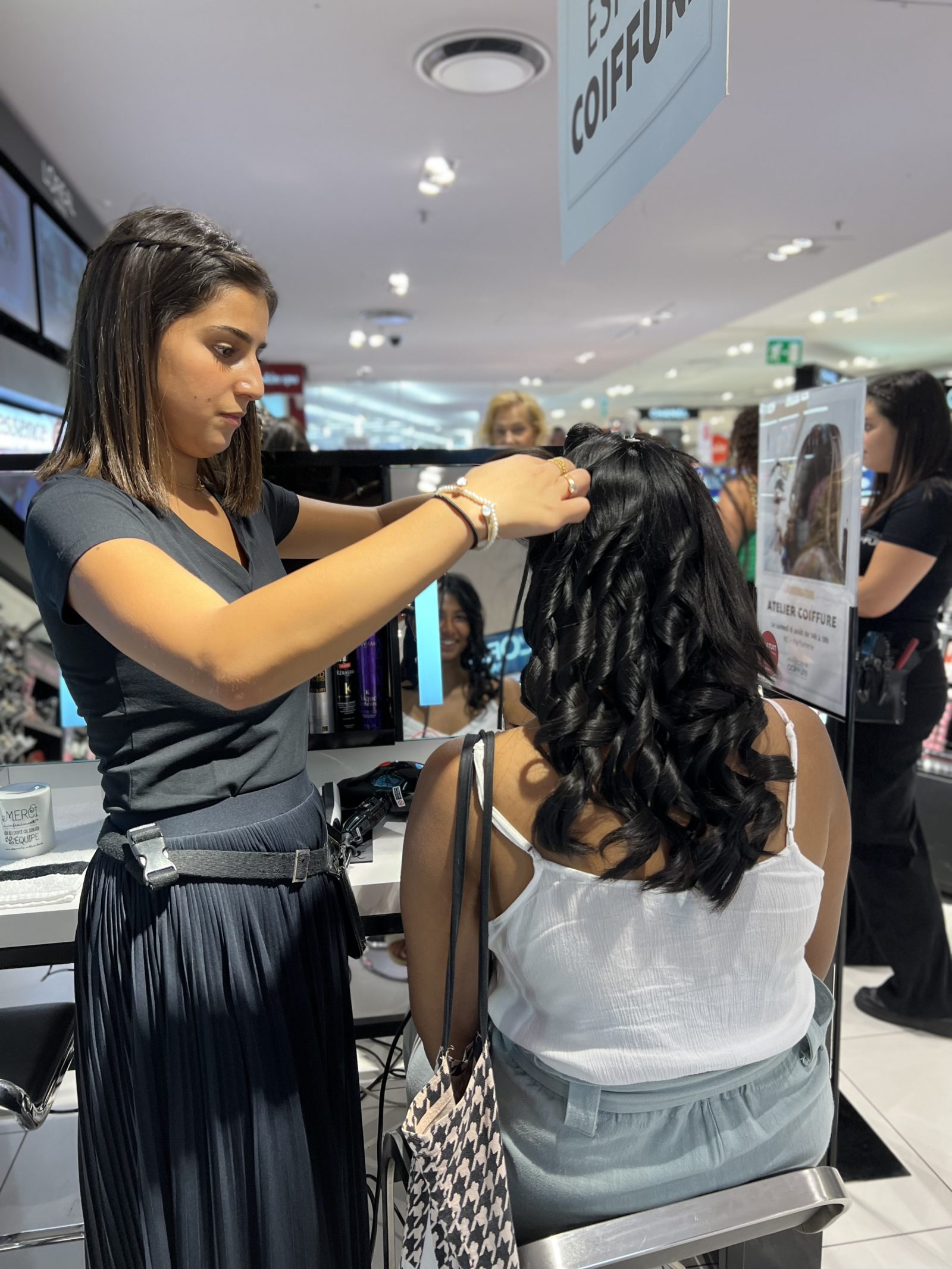 Travail de coiffure sur des cheveux longs bouclés dans un espace de salon
